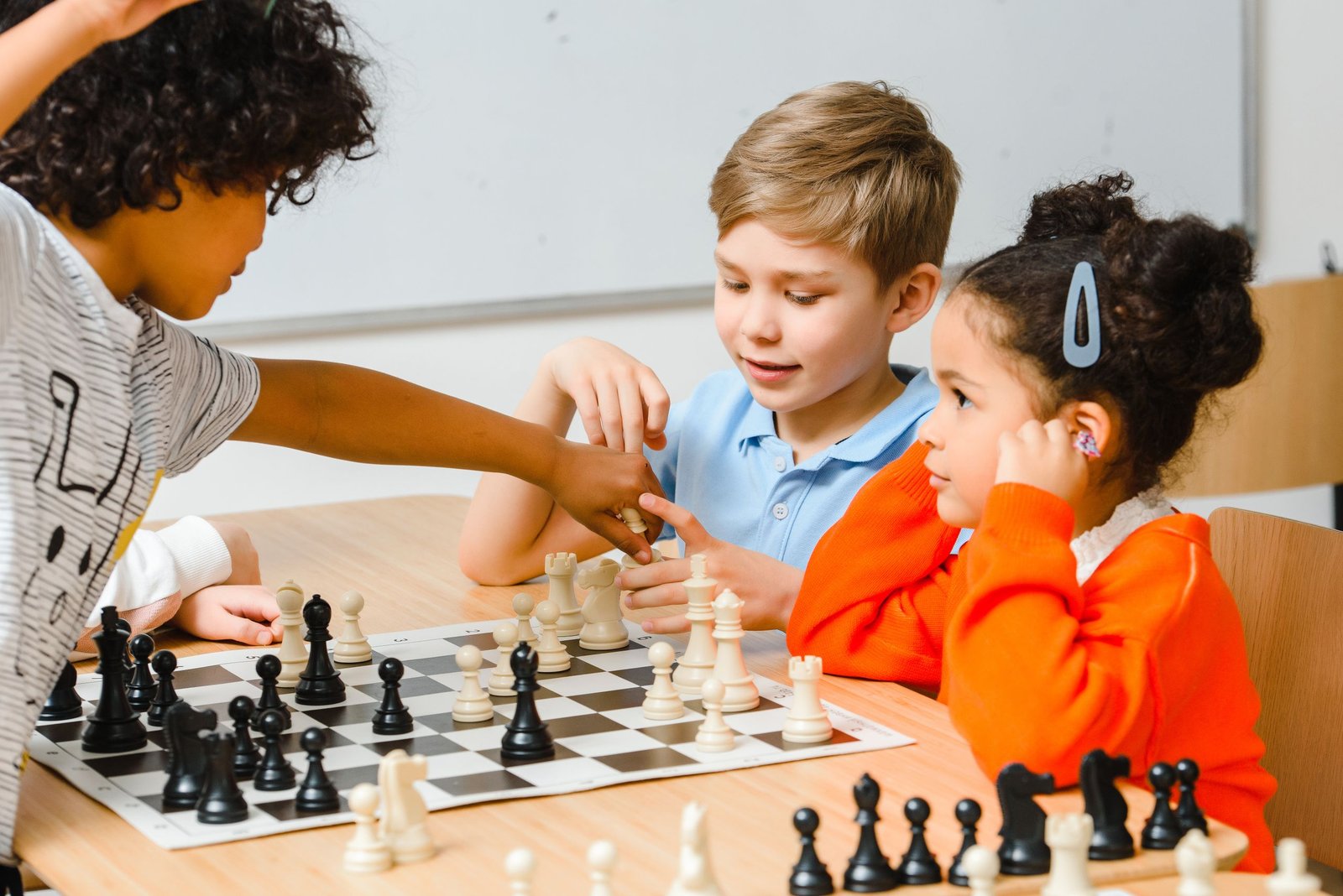 Niños aprendiendo y jugando al ajedrez en una clase de iniciación